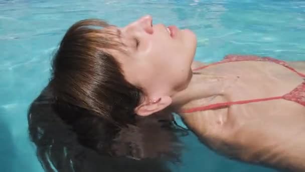 美丽的女人正脸朝下地漂浮在游泳池里 在暑假里放松 合上肖像 — 图库视频影像