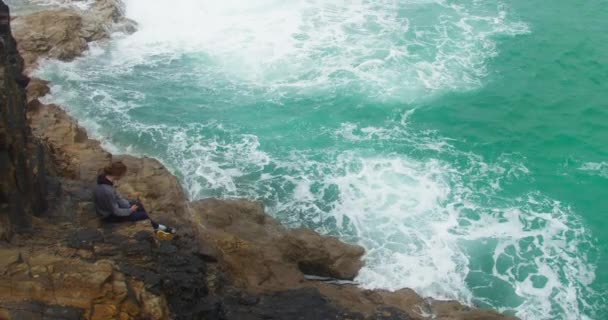 Einsamer Teenager Sitzt Auf Felsen Kliff Als Türkisfarbenes Ozeanwasser Gegen — Stockvideo