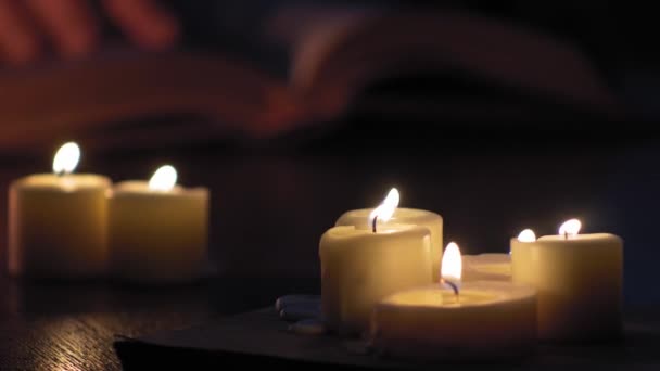 Man Hands Follow Lines Book While Lit Candles — ストック動画