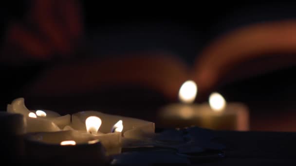 Man Hands Flip Pages Book While Lit Candles — Vídeo de stock