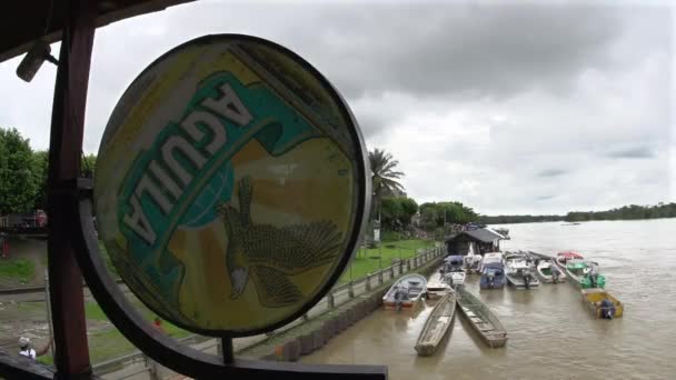 Boten Aangemeerd Langs Rivier Achter Een Verweerd Aguila Bier Teken — Stockvideo