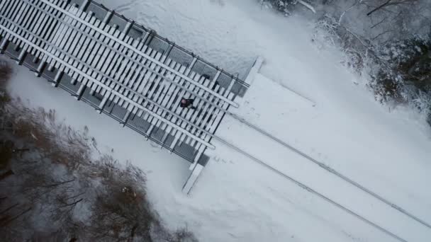 从上面望去 一个人走在雪地覆盖的铁轨上 — 图库视频影像