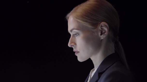 サイドプロフィール ポートレートのポートレート黒を背景にスタジオで撮影されたスーツ姿の若いビジネスマンの女性 — ストック動画