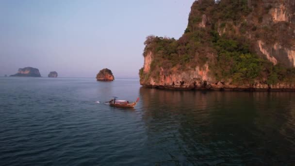 安达曼海日出时分 泰国克拉比海滩附近一艘泰族长尾船在一个独特的石灰岩岩层周围驾驶的中空飞行 — 图库视频影像
