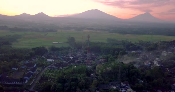 4つの山 Telomoyo Andong Merbabu Merapi を望む田舎の真ん中にあるセルラーアンテナ 日の出の空の火山 — ストック動画