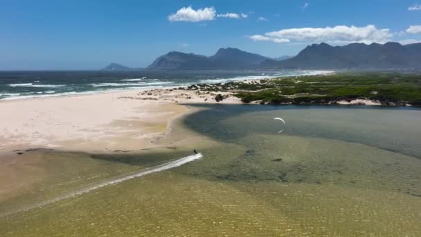 水平線の山脈を持つ南アフリカの砂の海岸線に近いカイトサーフィン — ストック動画
