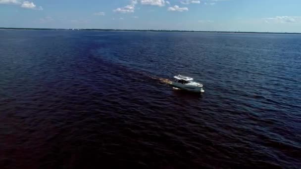 暗い水の地平線に沿って現代の白いモーターボートの空中ドローンショット 昼間のドローン 海水の上に太陽光パネルを備えた技術先進のモーターボートのトップビュー — ストック動画