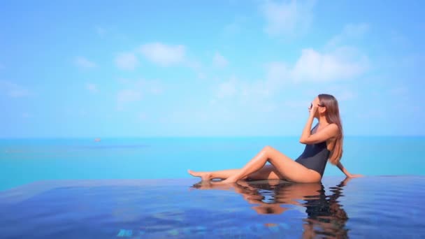 蓝色热带乐园 无边游泳池 绿松石海和蓝色夏日天空中身穿泳衣的瘦弱女子 — 图库视频影像