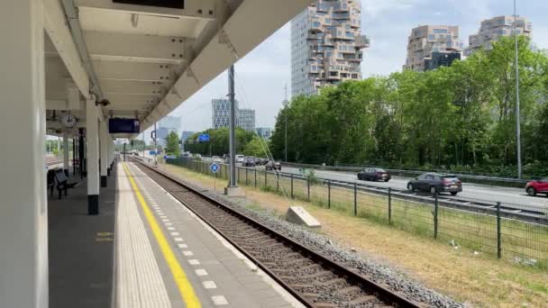 電車の駅とZuidas近くのアムステルダムで車を運転する高速道路でのプラットフォーム プラットフォームは空で 人はいません 車がたくさんある 駅はアムステルダム ザイド 高速道路はA10です — ストック動画