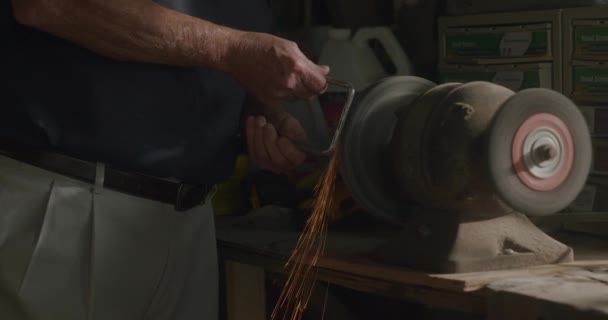 Older Man Grinds Metal Grindstone Morning Light Workbench Sparks Fly — Stock Video