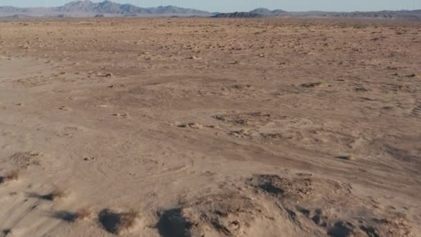遠くの山々と荒涼とした空の砂漠の風景の上を低飛行 — ストック動画