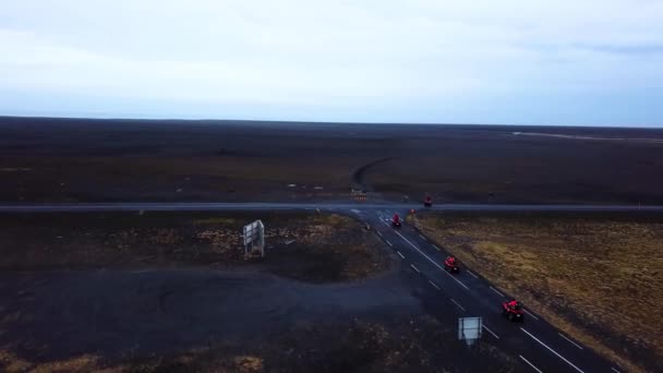 アイスランドの黒い砂のビーチを通る明るい赤いクワッドバイクの空中ビュー — ストック動画