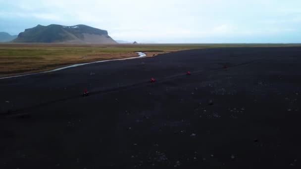 明亮的红色四驱车驶过冰岛黑色沙滩的空中景观 — 图库视频影像
