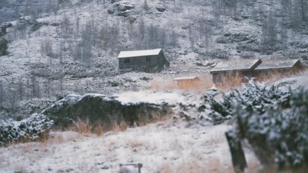雪に覆われた風景の中にいくつかの木造キャビン スローモーション パン右 — ストック動画