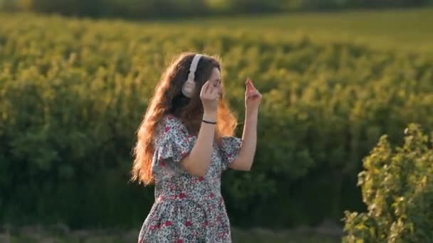 Kızıl Saçlı Kız Tarlada Kulaklıkla Yürüyor Şarkı Söylüyor Dans Ediyor — Stok video
