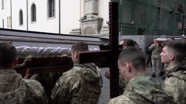 乌克兰士兵带领着一个由倒下的同志棺材组成的葬礼队伍 经过圣彼得和保罗的教堂外拿着木制十字架的士兵 — 图库视频影像