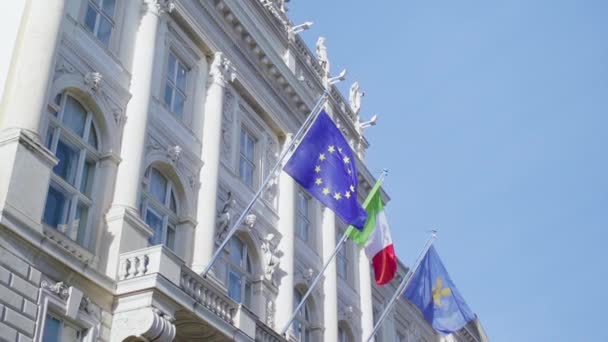 ภาพถ ายการเคล อนไหวช าของธงของสหภาพย โรปและอ ตาล แขวนอย บนอาคารใน Piazza Unita — วีดีโอสต็อก