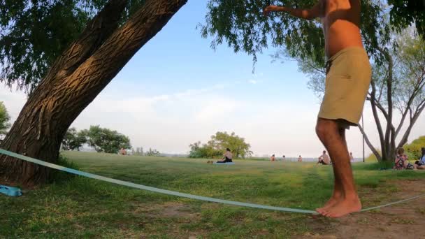 屋外公園でスラックライン上でバランスのとれた大人の男性の足の側面図 スローモーション — ストック動画