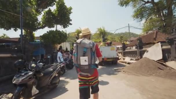 Mężczyzna Torbą Kempingową Białym Kapeluszem Spacerujący Ulicami Bali Indonezja — Wideo stockowe