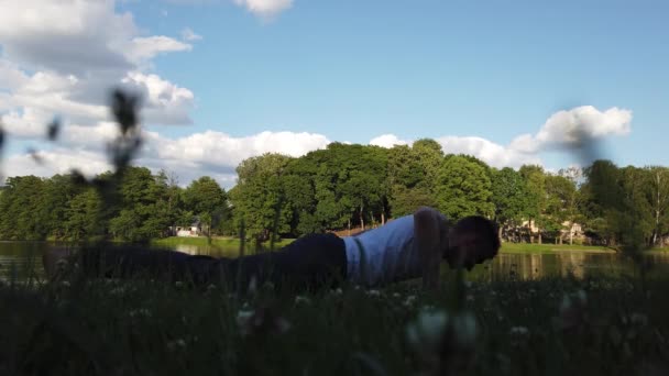 Egy Férfi Fekvőtámaszt Csinál Egy Parkban Egy Háttérben — Stock videók