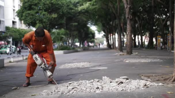 Arbeiter Orange Zertrümmern Gehweg Mit Presslufthammer Hintergrund Grüne Bäume Zeitlupe — Stockvideo
