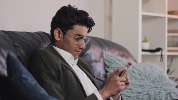 Young Excited Indian Man Enjoying Playing Games His Smartphone Couch — ストック動画