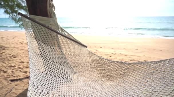 砂の熱帯のビーチの上に海の波が転がるように編まれたハンモックが空になる — ストック動画