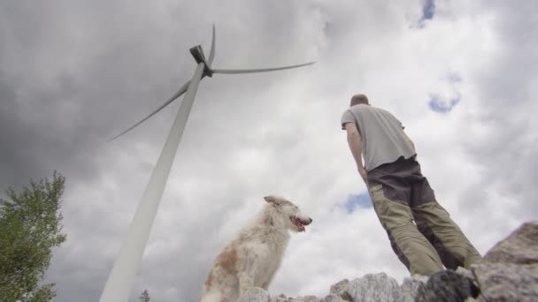 Man Och Hans Hund Står Ett Stort Vindkraftverk Innan Går — Stockvideo