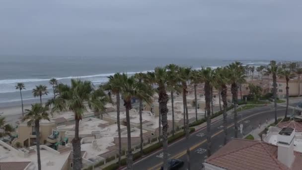 ビーチサイドコンドミニアムと人々は曇りの日にビーチで遊ぶサーフライディングバイクHdオーシャンズサイド サンディエゴ カリフォルニア州で水平空中ドローンショットを楽しんで — ストック動画