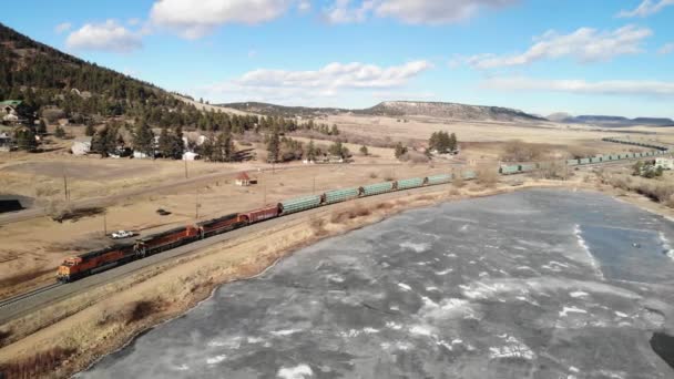 Juna Kulkee Vieressä Järven Rocky Mountains Kylmä Iltapäivä Aurinkoisena Päivänä — kuvapankkivideo