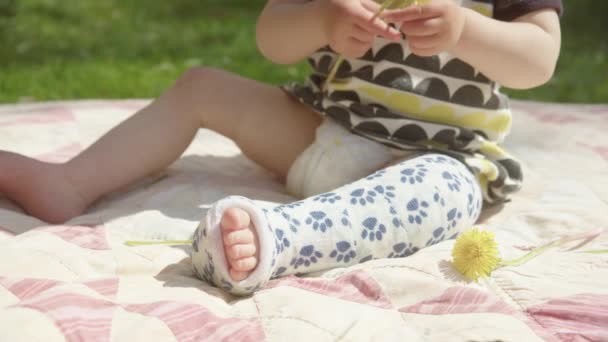 Closeup Pan Cute Toddler Playing Flowers Broken Leg — Stockvideo