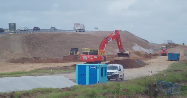 Crawler Excavator Scooping Soil Constructing New Road Traffic Moving Background — Video