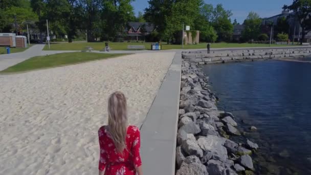 Rıhtımda Yürüyen Güzel Kırmızı Elbiseli Genç Kadınları Takip Ediyoruz — Stok video