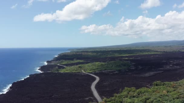 最近乾燥した溶岩流の上を飛行する広い空中ショットで ハワイのビッグアイランドでそれを横断する道路が切断されます — ストック動画