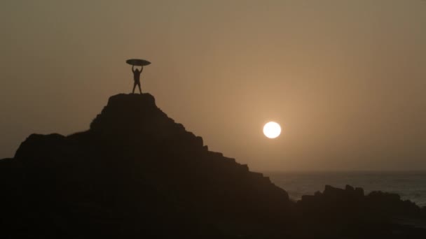 Silhouet Van Surfer Holding Surfboard Lucht Rocky Outcrop Het Strand — Stockvideo