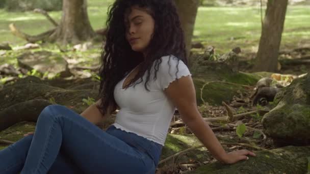 Smiling Hispanic Model Sitting Large Tree Trunk Park Setting Sunny — Αρχείο Βίντεο