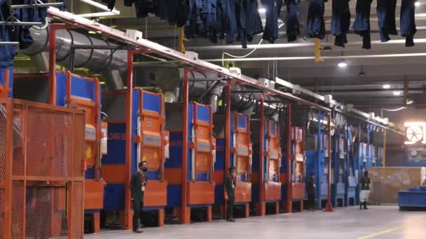 Rows Large Industrial Machines Workers Standing Next Them Jeans Hanging — Vídeo de stock