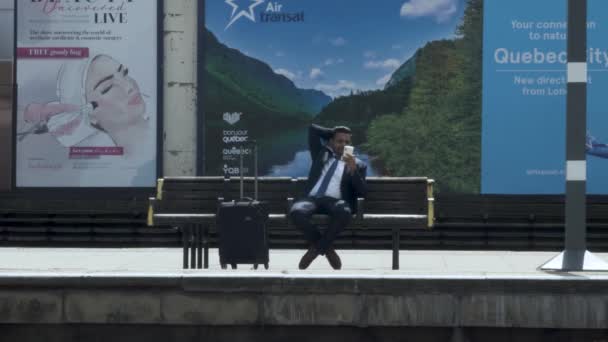Asian Businessman Seated Station Platform Browsing His Phone Londen Mei — Stockvideo