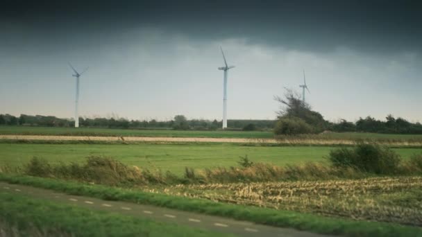 緑豊かなフィールド上の風力タービン 暗い嵐の雲が急速に上に移動します スローモーション パンフォロー — ストック動画