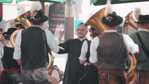 在慕尼黑 巴伐利亚铜管乐队身穿传统的莱德霍森服装 头戴羽毛帽 在阳光灿烂的日子里演奏音乐 巴伐利亚传统深受游客欢迎 — 图库视频影像
