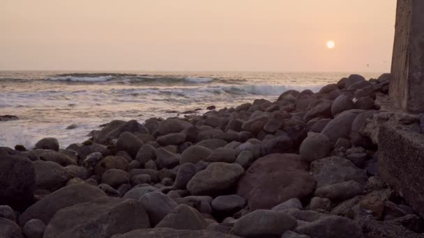 Statyczne Ujęcie Zachodzącego Słońca Nad Horyzontem Kamienistą Plażą Pierwszym Planie — Wideo stockowe