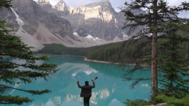 Ένας Χαρούμενος Ταξιδιωτικός Φωτογράφος Στέκεται Κοντά Μια Γαλάζια Λίμνη Κοντά — Αρχείο Βίντεο