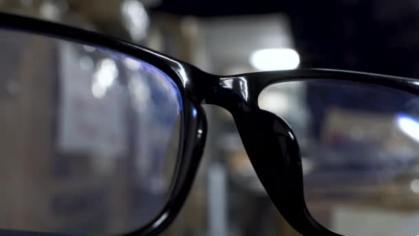 Rafları Karıştıran Bokeh Erkek Arkaplanlı Siyah Yüzüklü Gözlüklerin Yakın Görüntüsü — Stok video