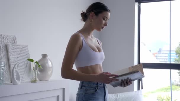 Female Model Sports Bra Denim Jeans Reading Book Living Room — Stockvideo