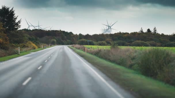 Danimarka Kırsalında Iki Şeritli Bir Yol Yavaşça Dönen Rüzgar Türbinleri — Stok video