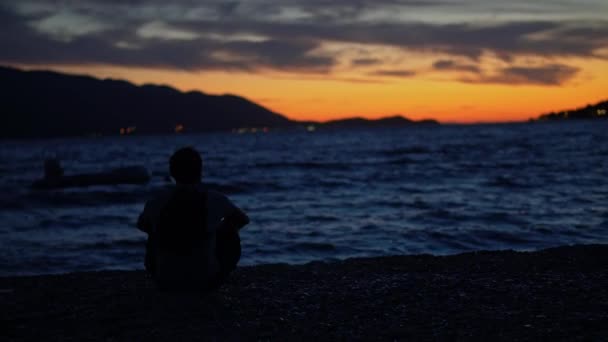 Jovem Sentado Uma Praia Areia Tranquila Assistindo Pôr Sol Sobre — Vídeo de Stock