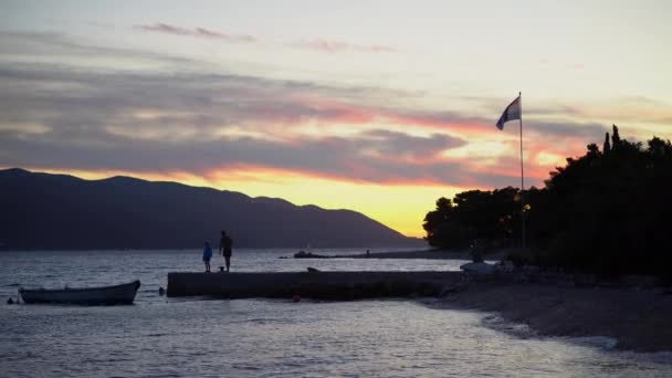日没時に船で桟橋の端に立つシルエットの人々 — ストック動画