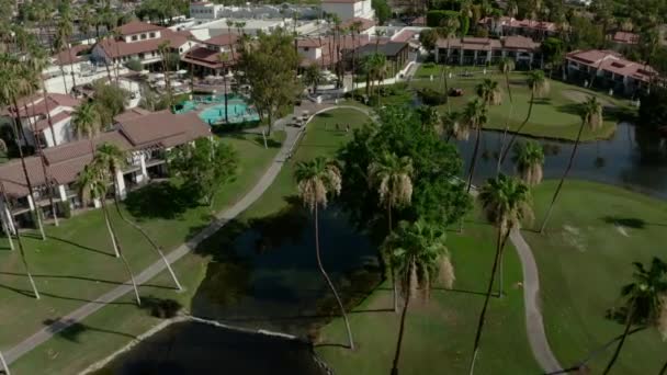 在一个阳光明媚的日子里 加利福尼亚棕榈泉的豪华住宅的空中无人侦察机中带着游泳池 旁边是绿色高尔夫球场 — 图库视频影像