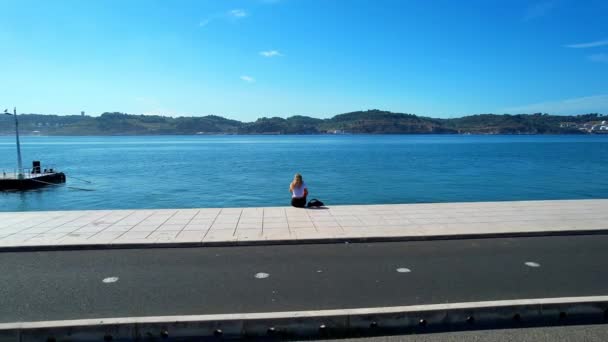 Vista Aérea Uma Rapariga Loira Sentada Junto Rio Tejo Lisboa — Vídeo de Stock