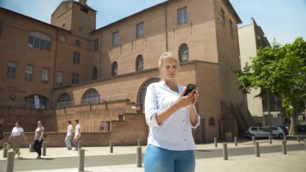 Uma Mulher Loira Com Cabelo Amarrado Cidade Usa Seu Smartphone — Vídeo de Stock